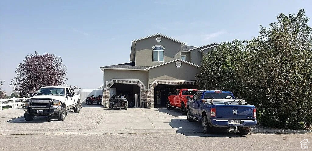 View of front of property featuring stucco siding, concrete driveway, a garage, and stone siding