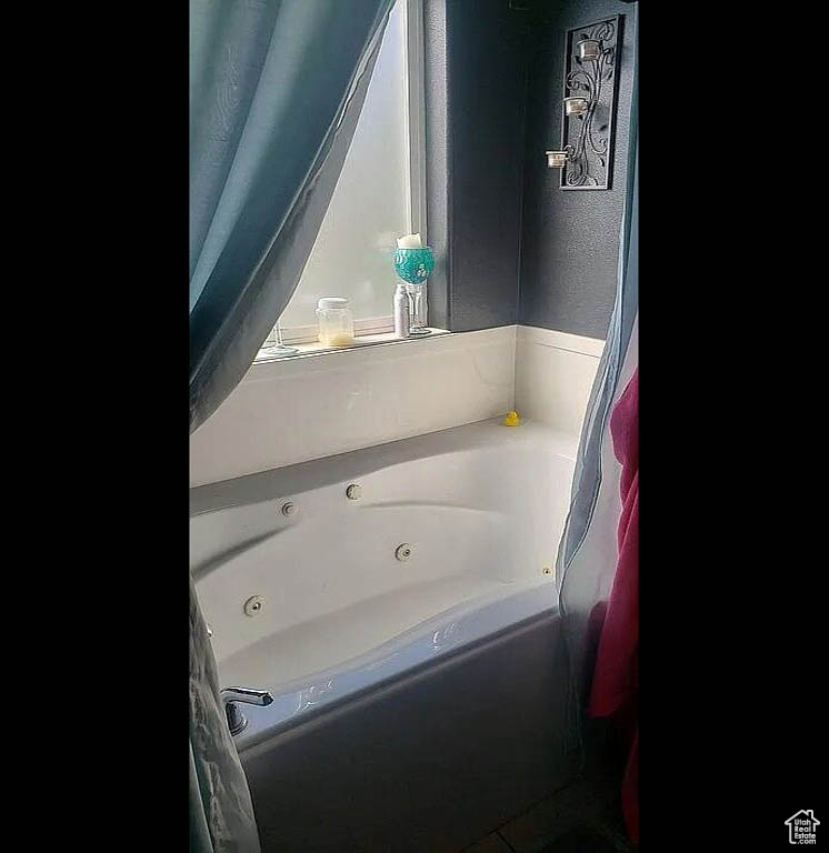 Full bathroom with a jetted tub and a textured wall