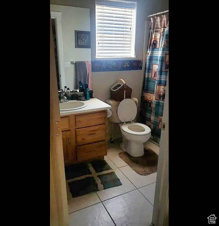 Bathroom with tile patterned floors, vanity, toilet, and a shower with curtain