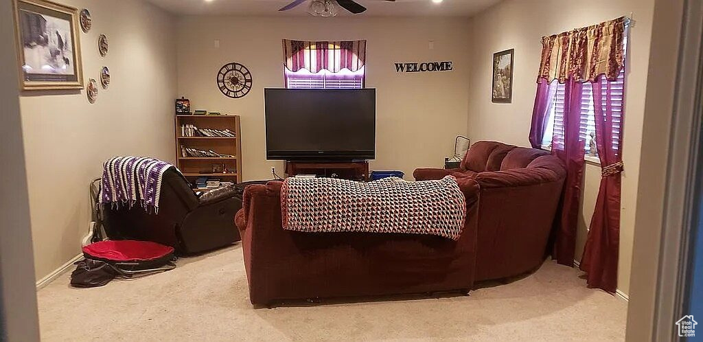 Living room with light carpet, ceiling fan, and baseboards