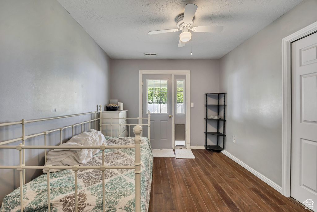 Bedroom featuring dark wood-style floors, baseboards, a textured ceiling, and a ceiling fan