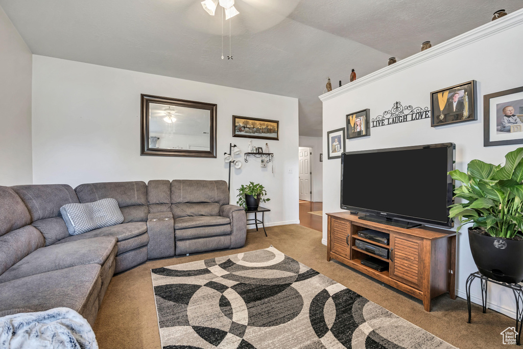 Living area featuring carpet, a ceiling fan, vaulted ceiling, and baseboards