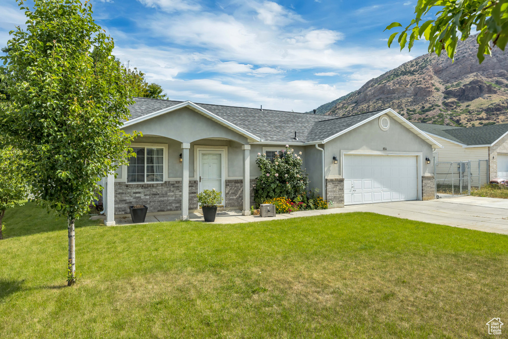 Ranch-style home featuring stucco siding, a garage, driveway, and a front lawn