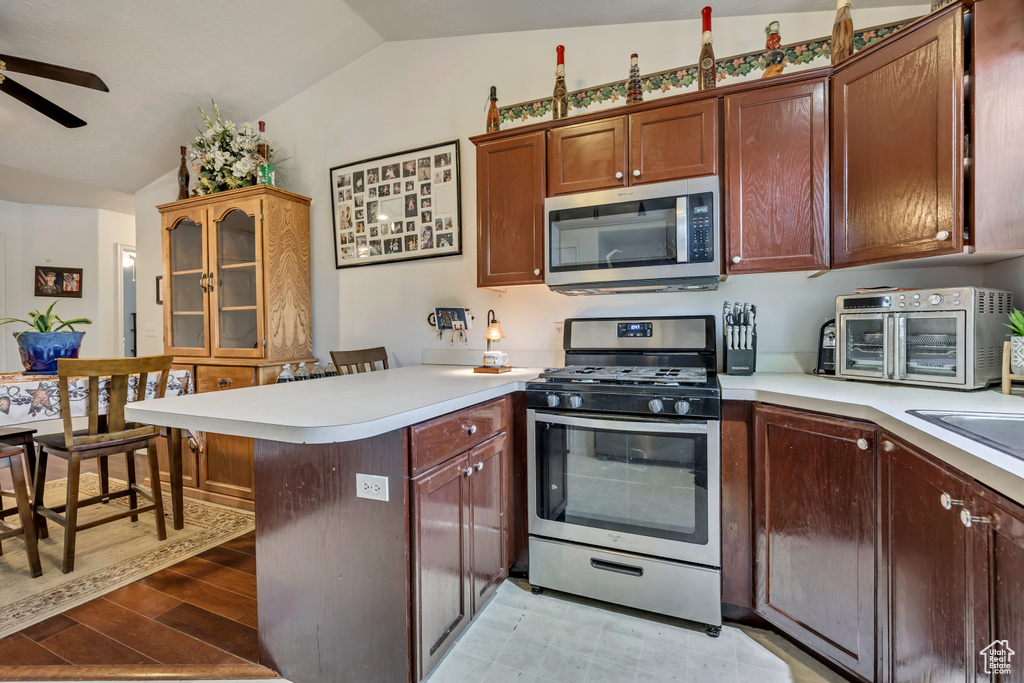 Kitchen with appliances with stainless steel finishes, lofted ceiling, a peninsula, ceiling fan, and light countertops