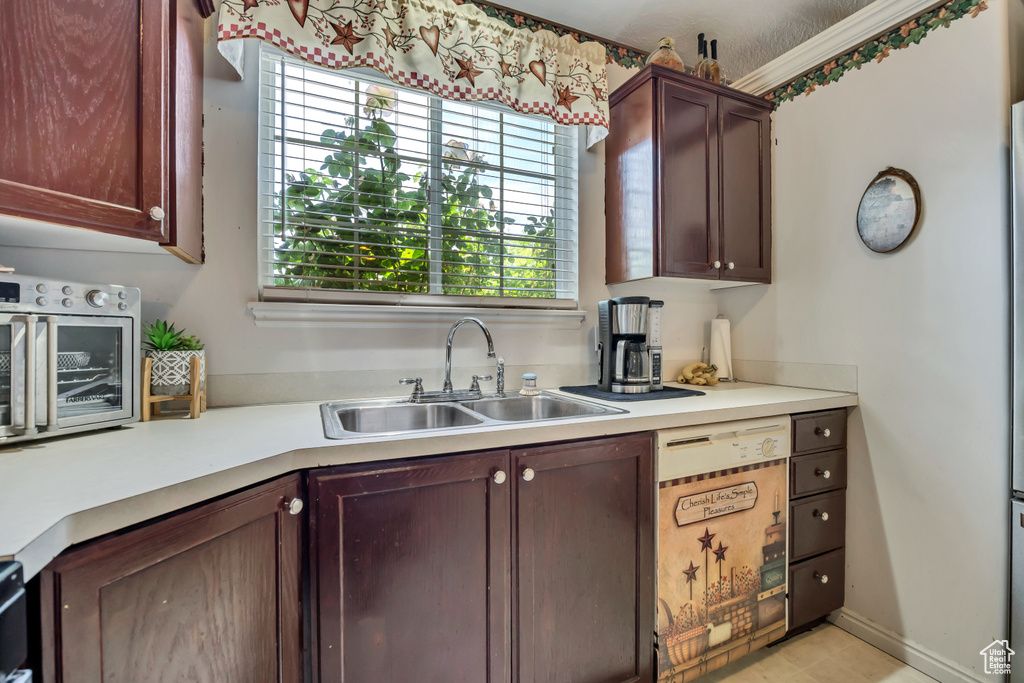 Kitchen with a sink, light countertops, and white dishwasher