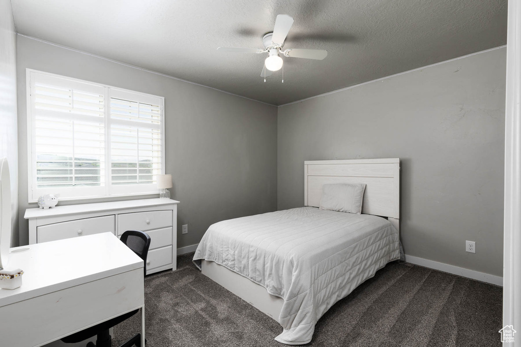 Bedroom with dark colored carpet, baseboards, a ceiling fan, and an office area