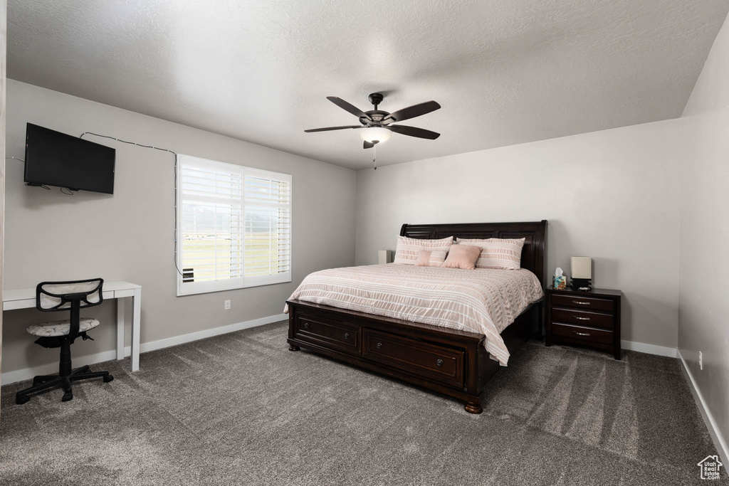 Bedroom featuring baseboards, dark carpet, and ceiling fan