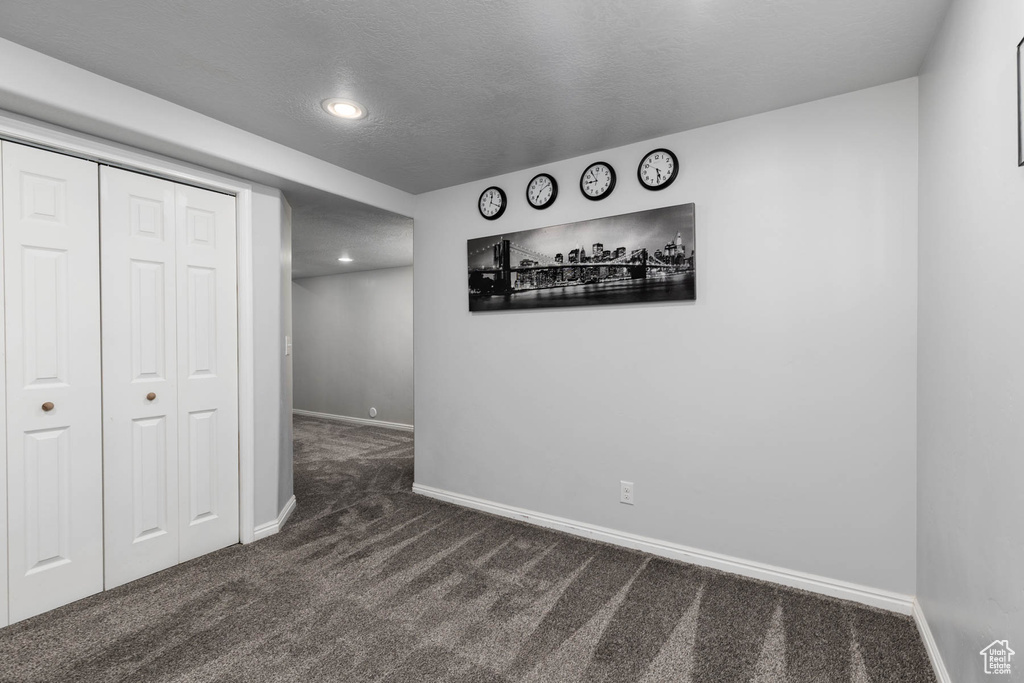 Unfurnished bedroom featuring dark carpet, baseboards, a closet, and recessed lighting