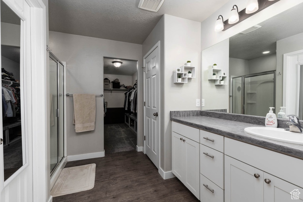 Full bath with a spacious closet, vanity, a shower stall, and a textured ceiling