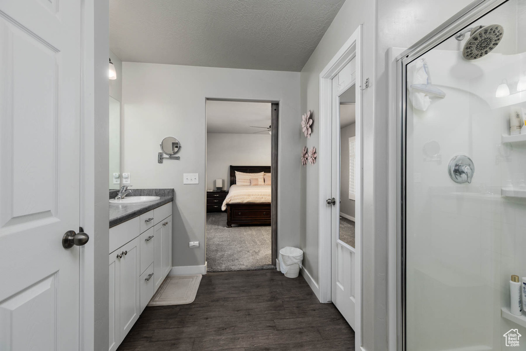 Ensuite bathroom featuring a stall shower, vanity, wood finished floors, a ceiling fan, and a textured ceiling
