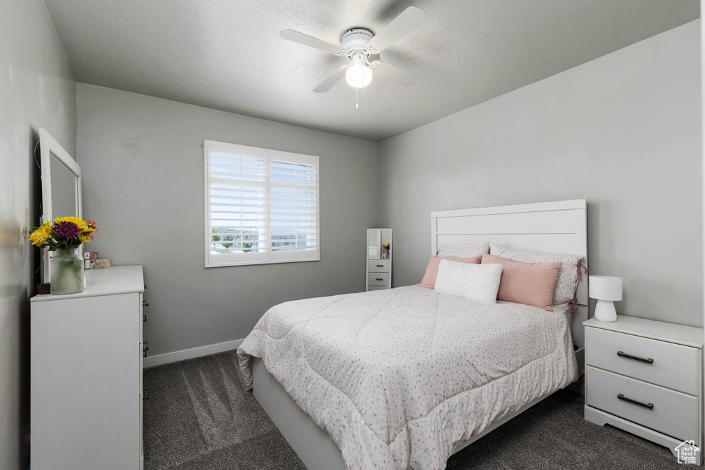Bedroom with dark carpet, baseboards, and ceiling fan