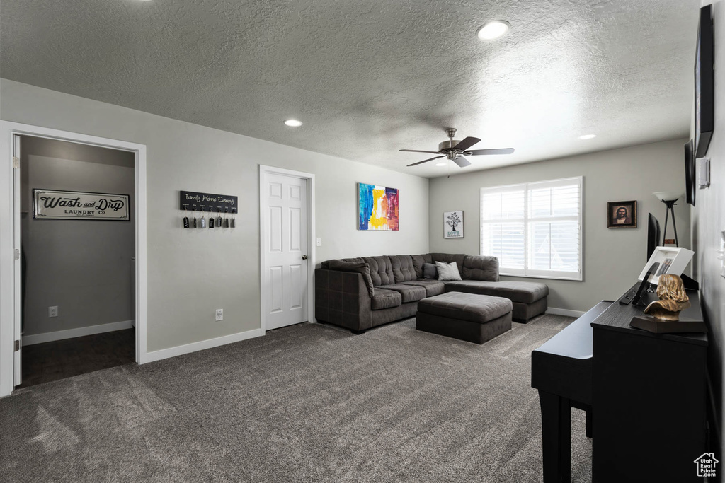 Living room with dark colored carpet, ceiling fan, baseboards, a textured ceiling, and recessed lighting