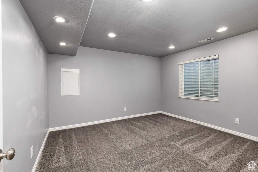 Unfurnished room featuring dark carpet, baseboards, recessed lighting, and a textured ceiling