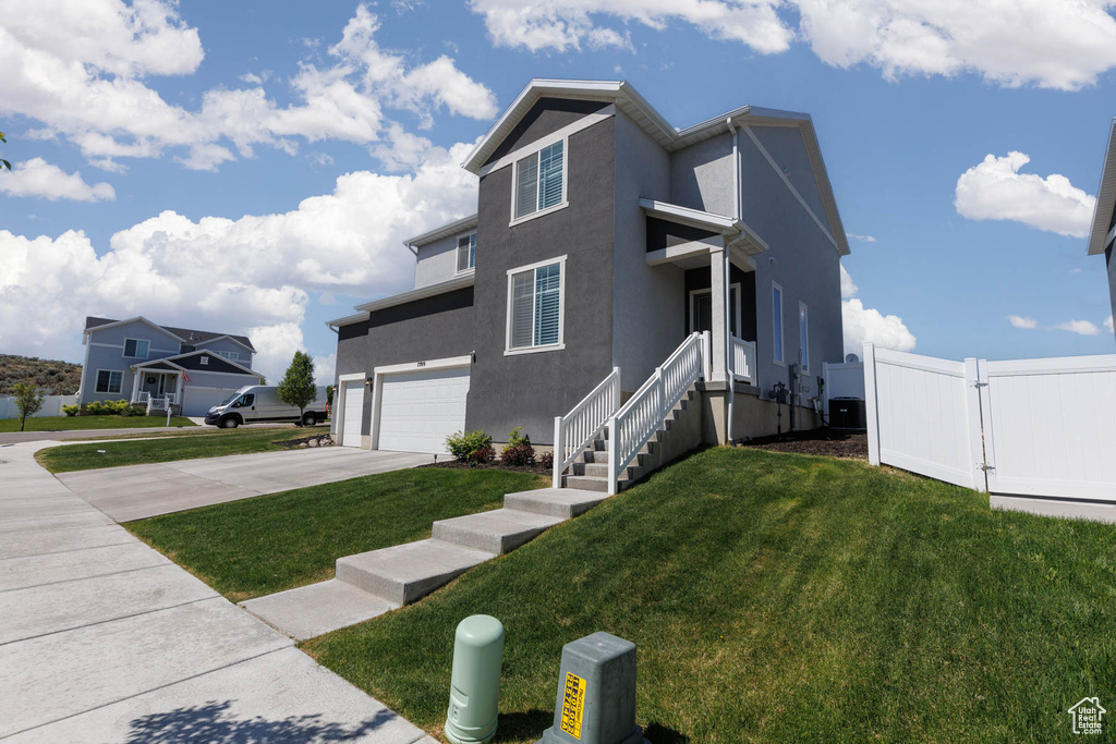 View of front facade with a garage, driveway, and stucco siding