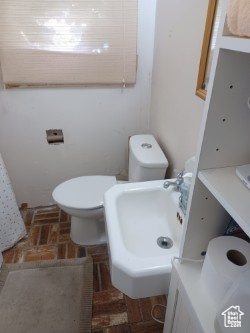 Bathroom with brick floors, a sink, and toilet