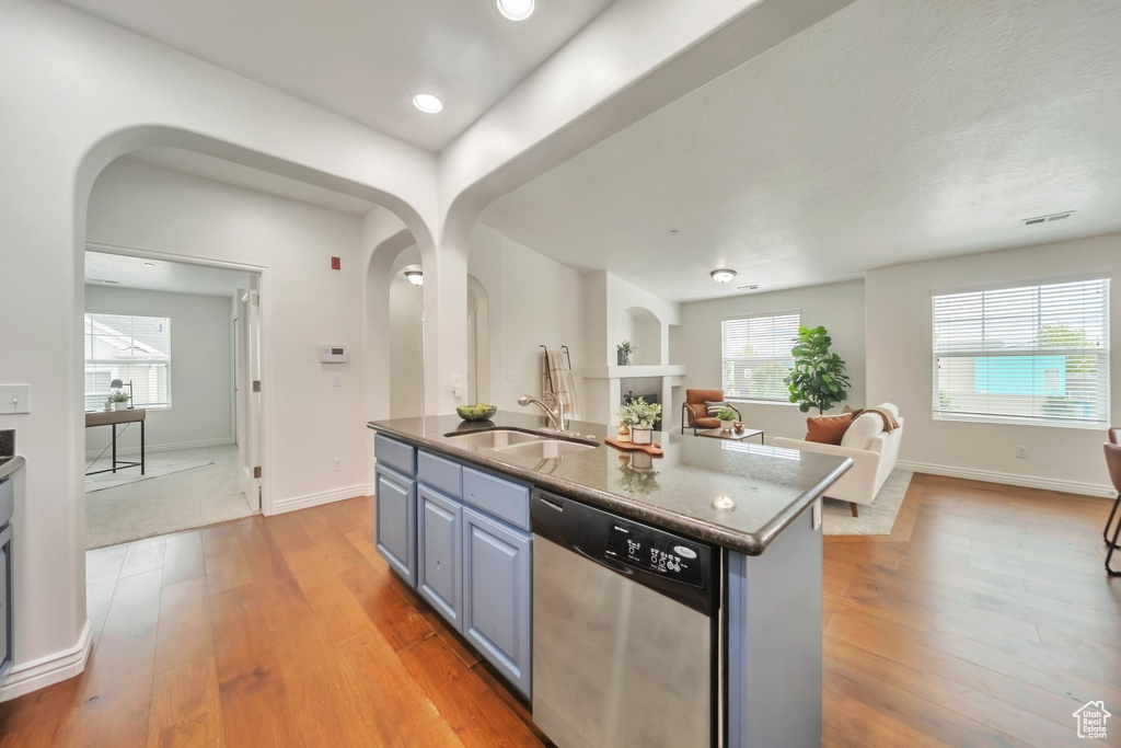 Kitchen featuring stainless steel dishwasher, a sink, arched walkways, open floor plan, and recessed lighting