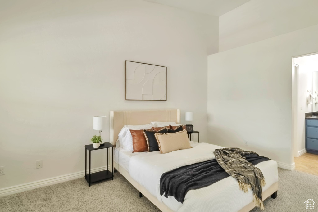 Bedroom with light colored carpet, baseboards, and ensuite bathroom