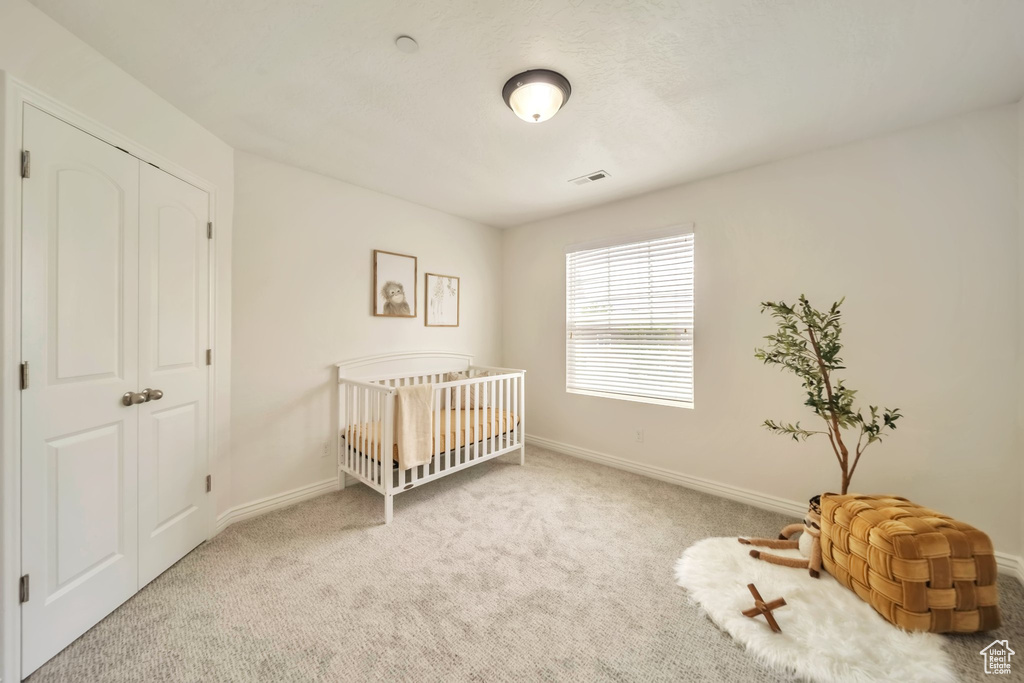Carpeted bedroom featuring baseboards and a nursery area