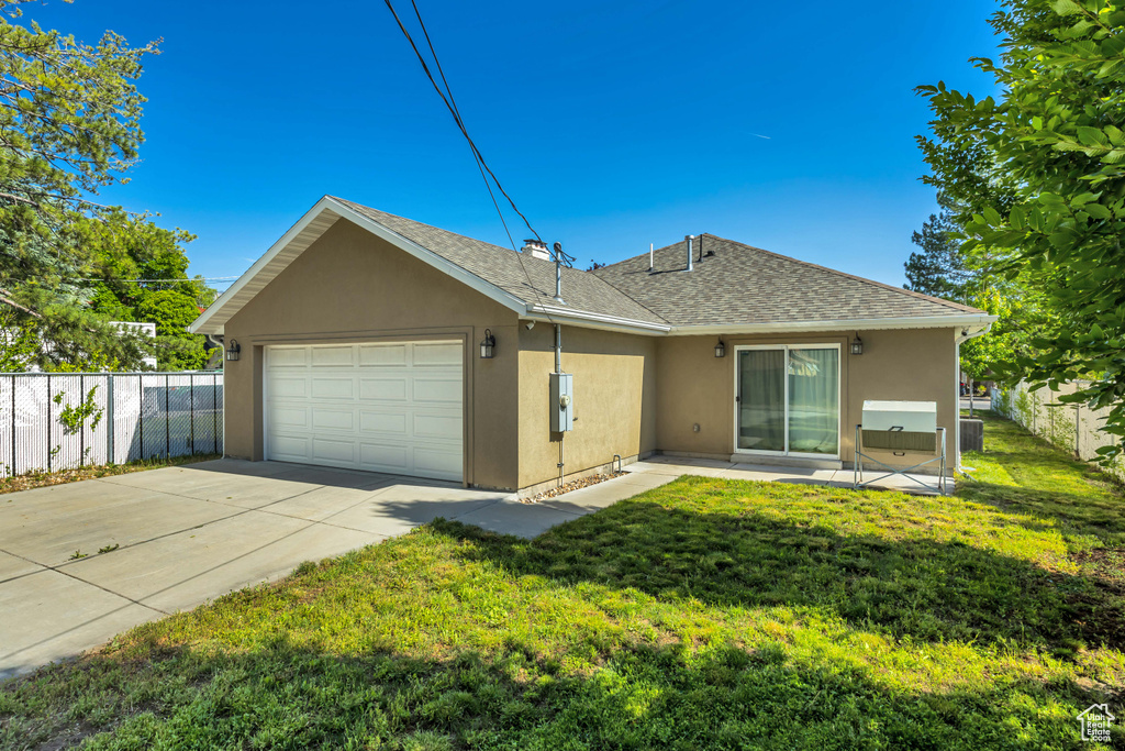 Back of property featuring stucco siding, a garage, concrete driveway, and a shingled roof