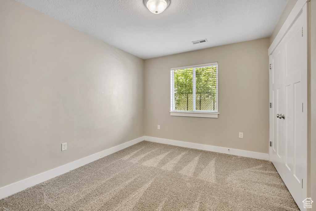 Spare room featuring carpet, baseboards, and a textured ceiling