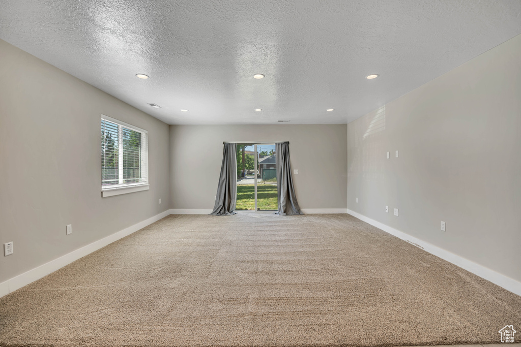 Unfurnished room featuring light carpet, recessed lighting, a textured ceiling, and baseboards