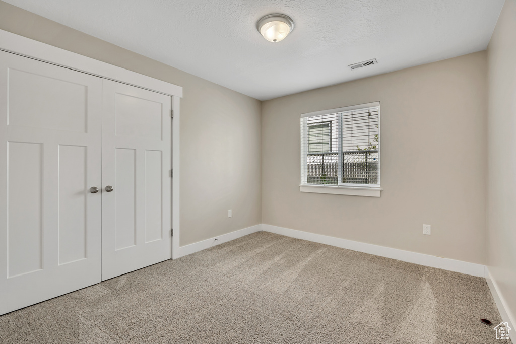 Unfurnished bedroom featuring carpet, baseboards, a closet, and a textured ceiling