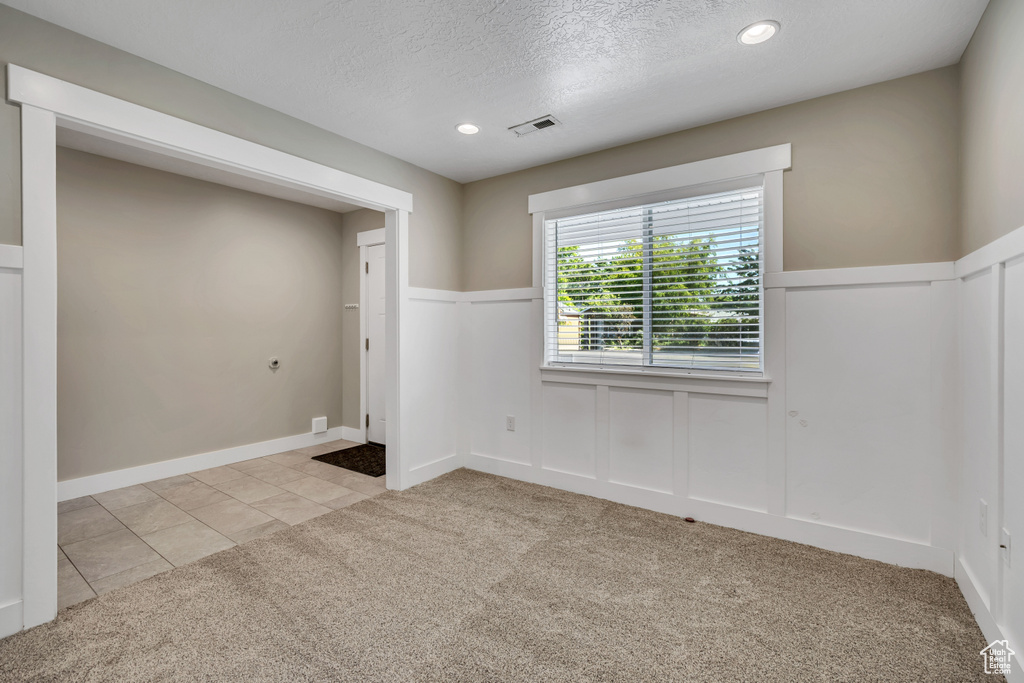 Unfurnished room featuring carpet floors, a wainscoted wall, a textured ceiling, recessed lighting, and a decorative wall