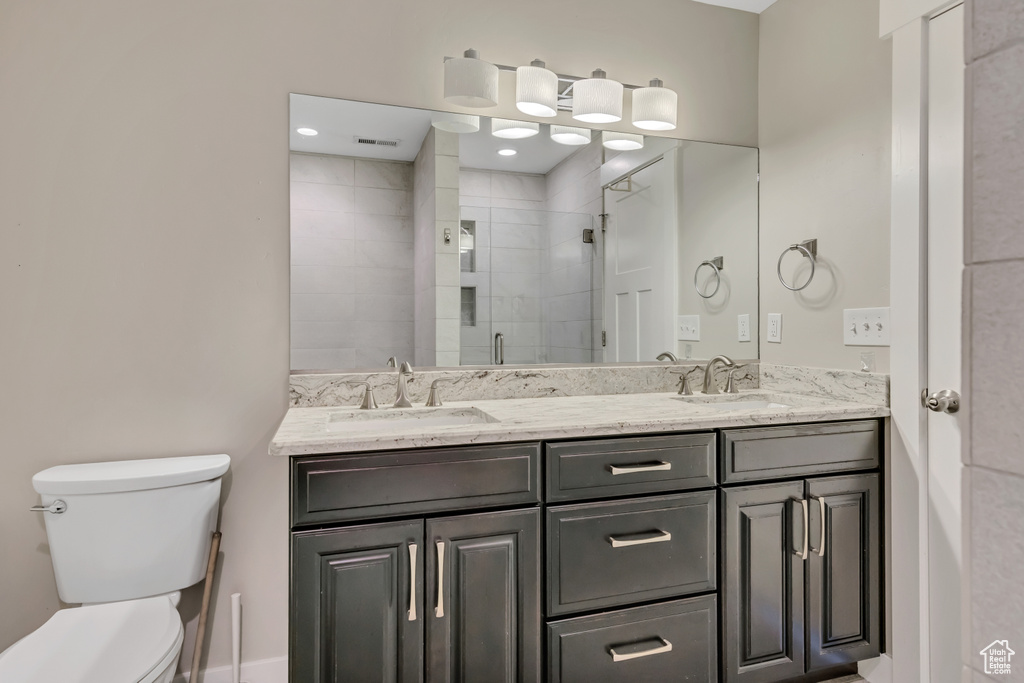 Full bathroom featuring toilet, double vanity, and a stall shower