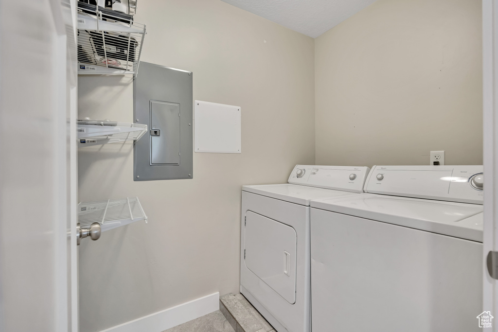 Laundry room with electric panel, washing machine and dryer, and baseboards