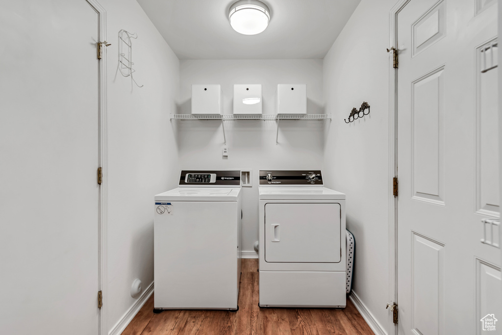 Laundry area with washing machine and clothes dryer, wood finished floors, and baseboards