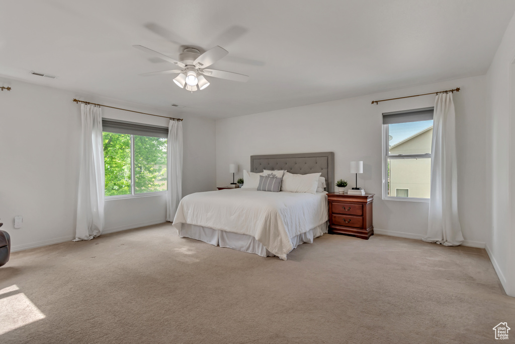 Carpeted bedroom with multiple windows, baseboards, and ceiling fan