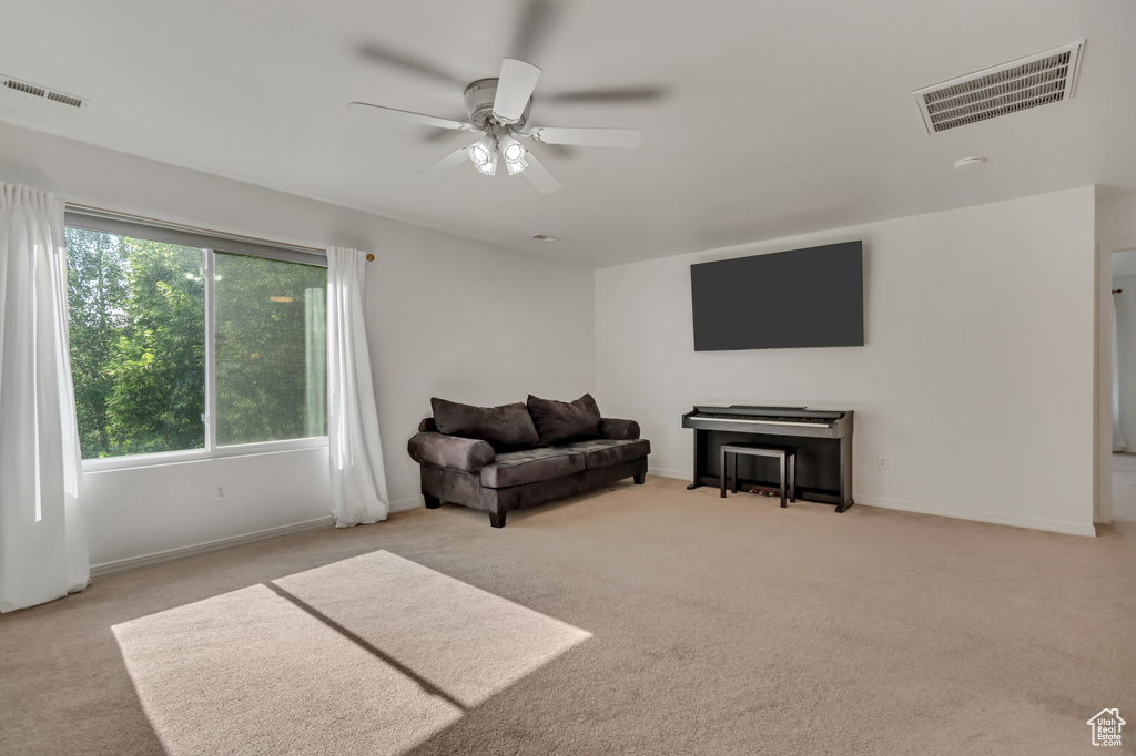 Living area featuring carpet, a ceiling fan, healthy amount of natural light, and baseboards