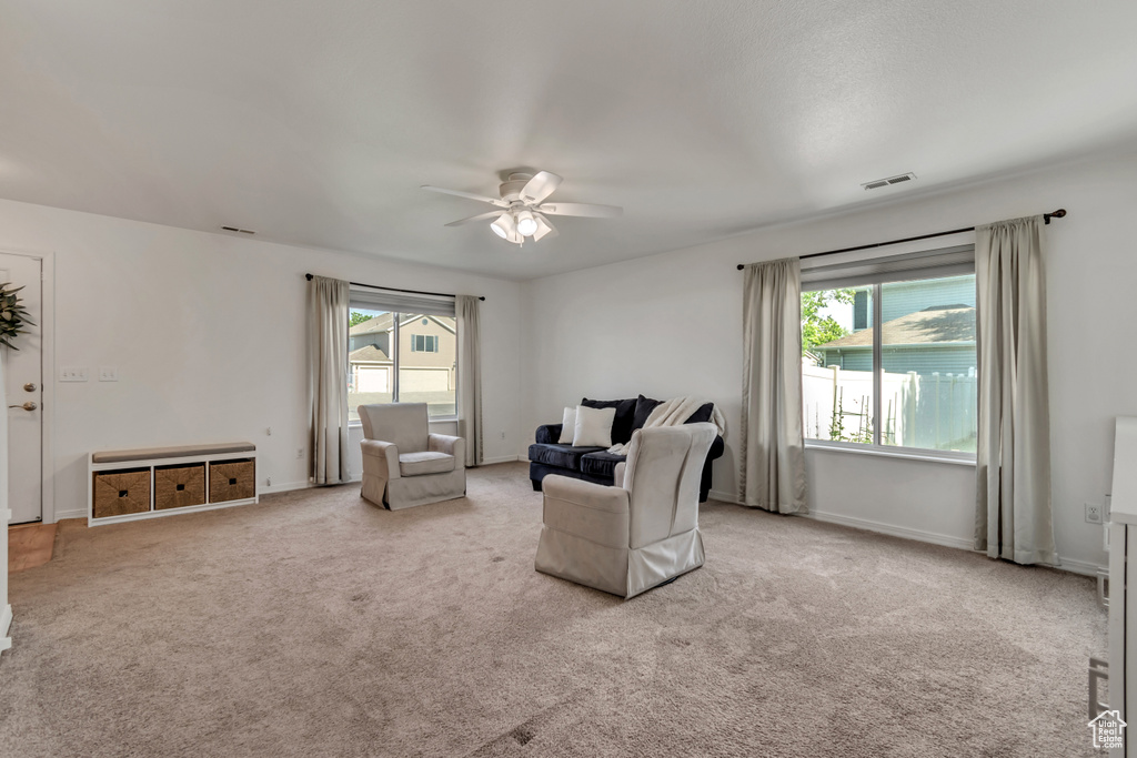 Living room featuring ceiling fan, healthy amount of natural light, carpet, and baseboards