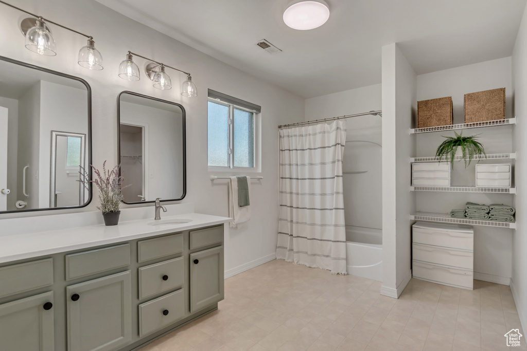 Full bath with vanity, shower / bath combo, and baseboards