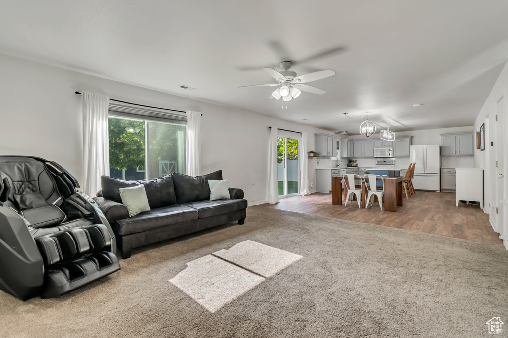 Living room featuring light colored carpet, healthy amount of natural light, a ceiling fan, and baseboards