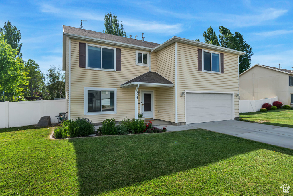 Traditional-style home featuring an attached garage and driveway