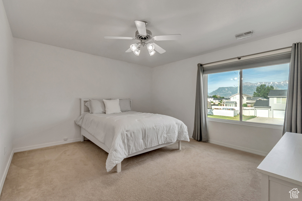 Bedroom with light carpet, baseboards, and ceiling fan