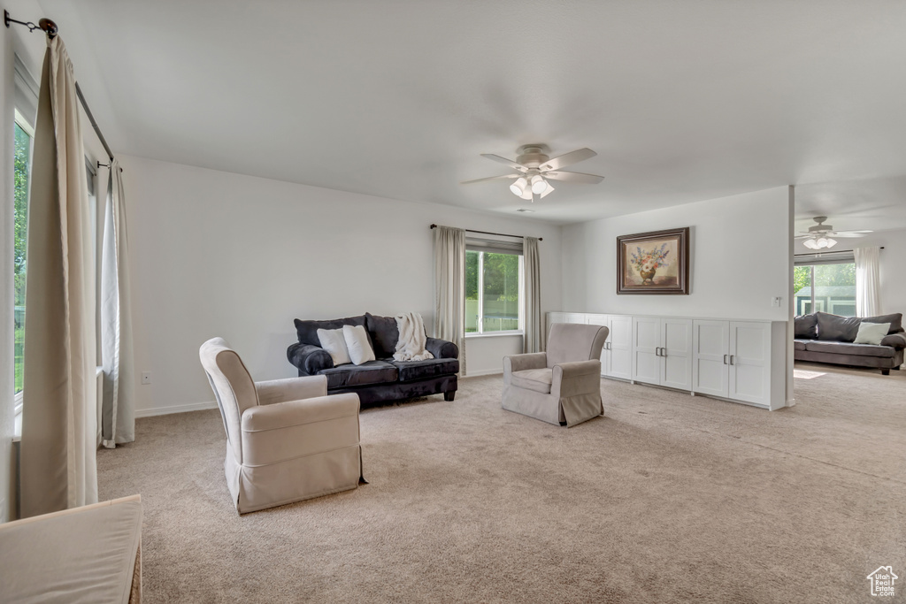 Living room featuring ceiling fan, light colored carpet, and healthy amount of natural light