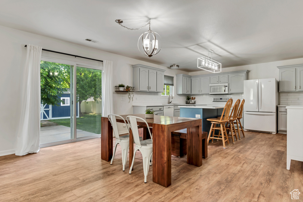 Kitchen featuring white appliances, gray cabinets, a sink, and tasteful backsplash