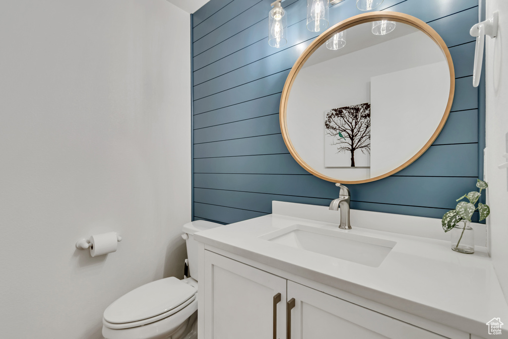 Bathroom with vanity, toilet, and wooden walls