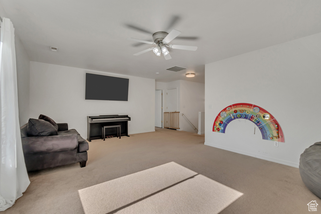 Living area with ceiling fan and light colored carpet