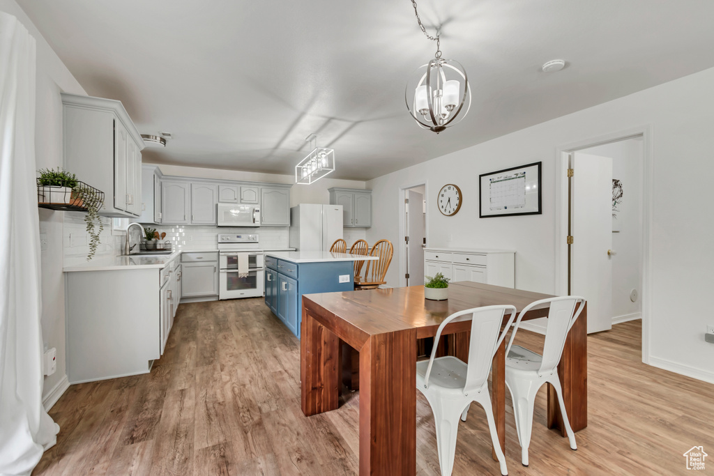 Dining space with light wood-style flooring, a chandelier, and baseboards