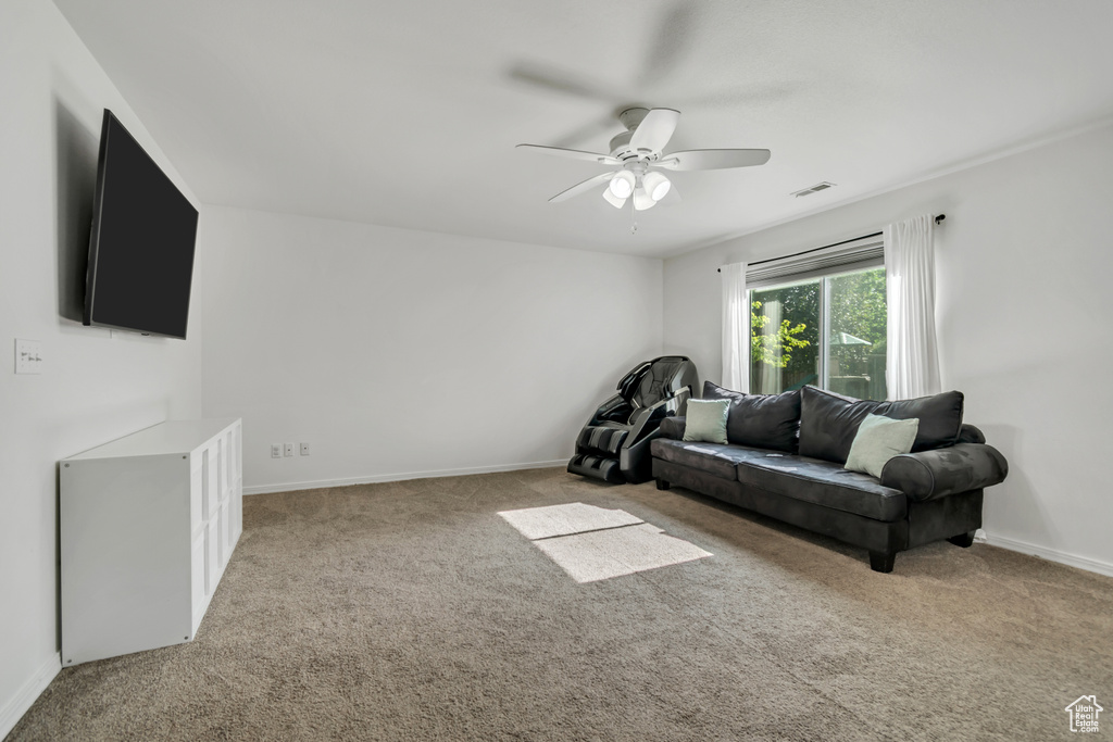 Living room featuring a ceiling fan, carpet, and baseboards