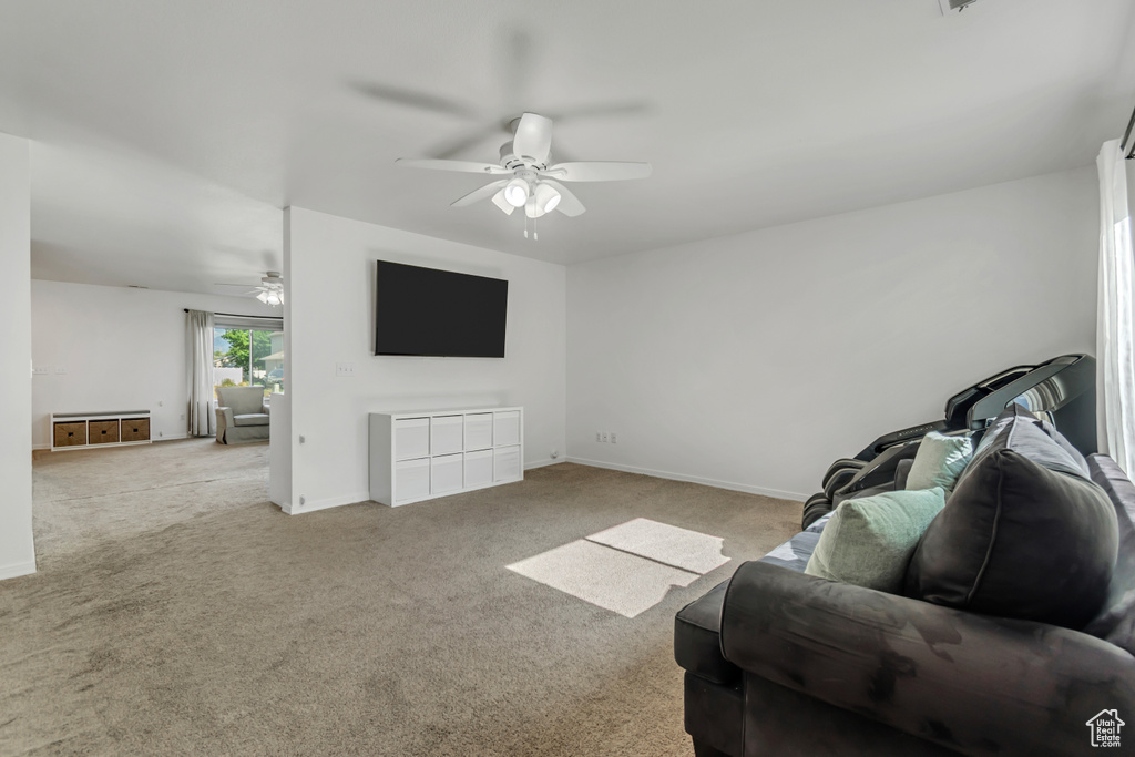 Living area with a ceiling fan, carpet, and baseboards