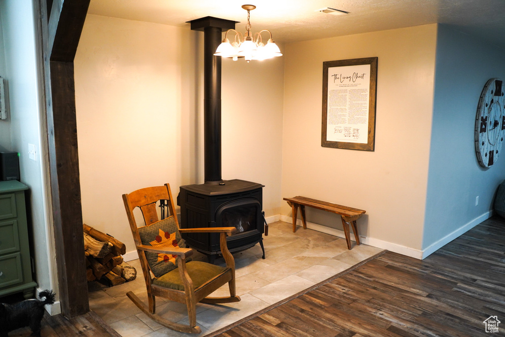 Living area with a wood stove, wood finished floors, baseboards, and a chandelier