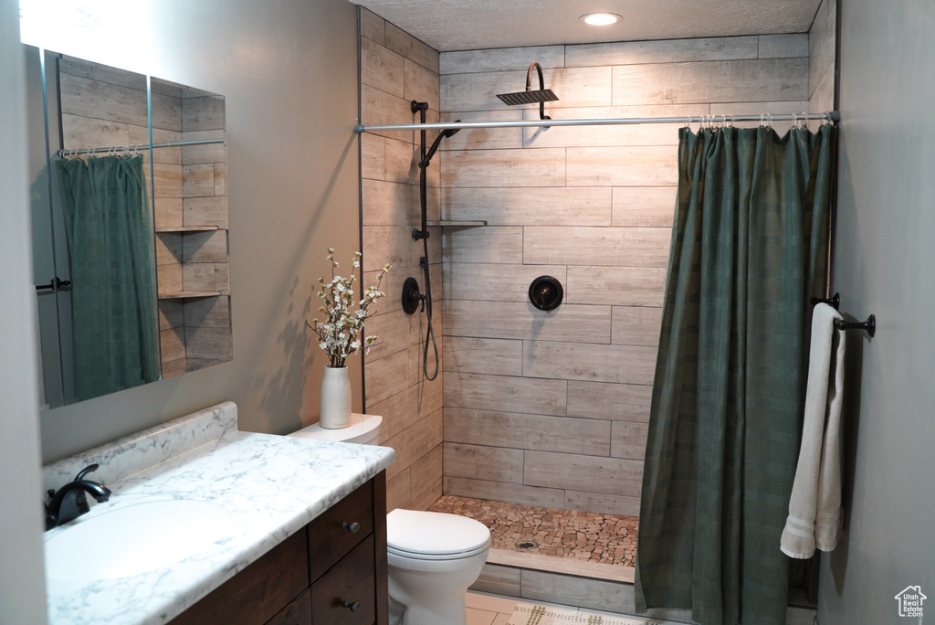 Full bath with toilet, vanity, and tiled shower