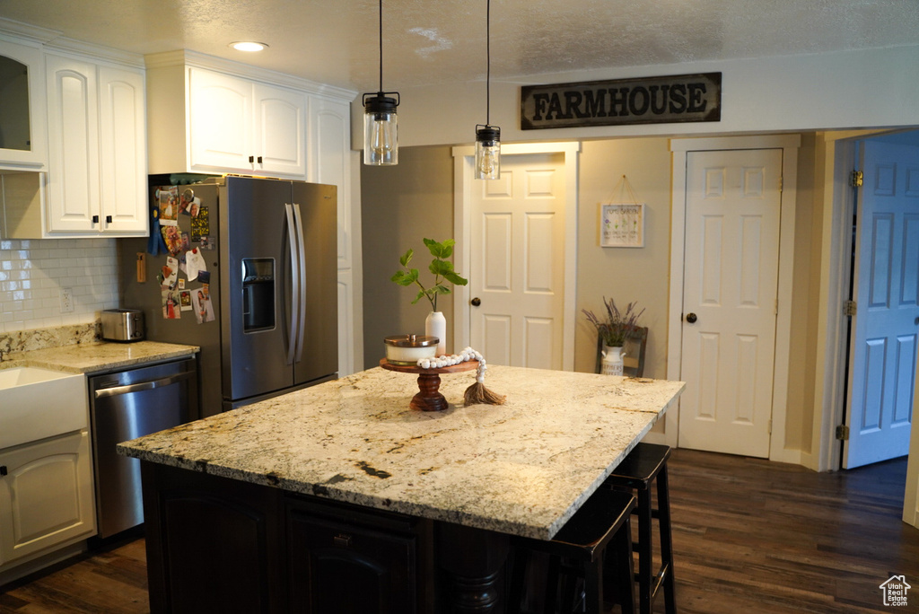 Kitchen with appliances with stainless steel finishes, dark wood-style flooring, recessed lighting, white cabinetry, and light stone counters