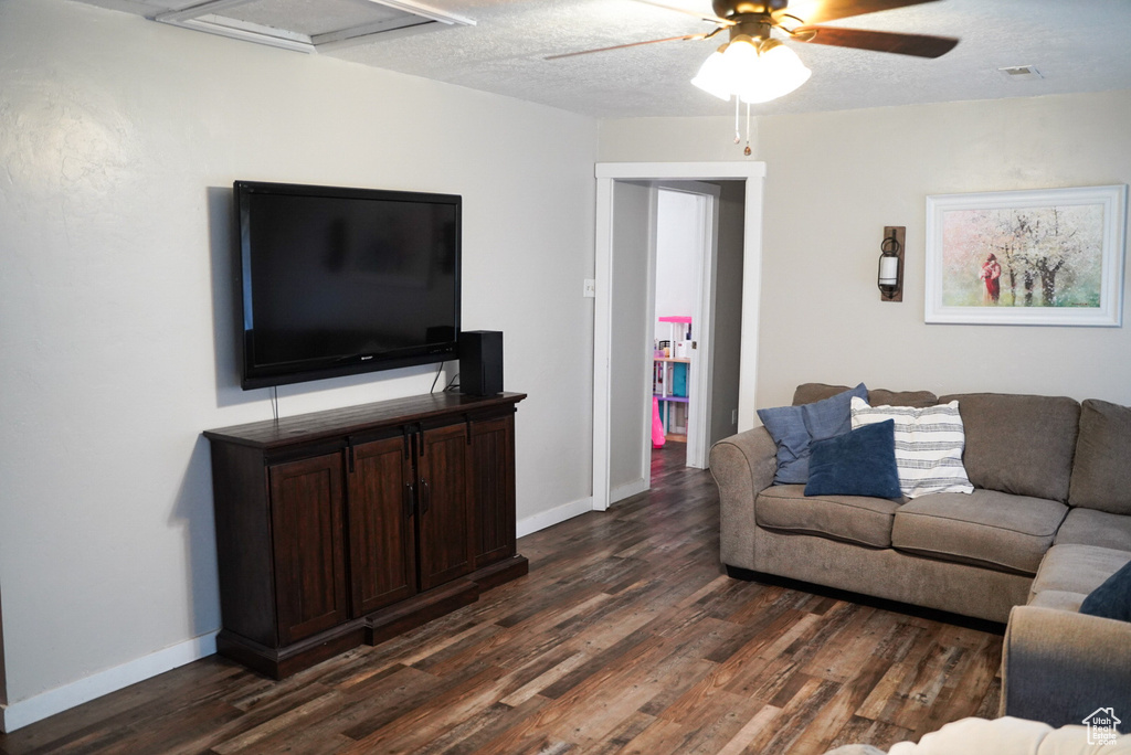 Living area with dark wood-style flooring, a ceiling fan, and baseboards