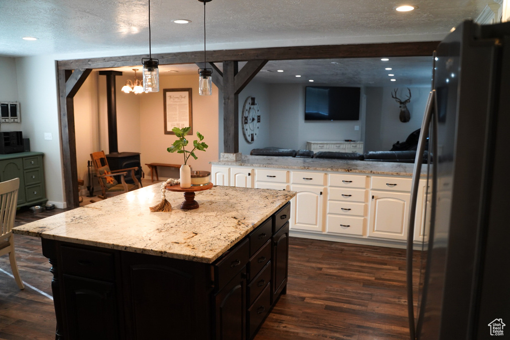 Kitchen featuring freestanding refrigerator, open floor plan, white cabinets, a wood stove, and a center island