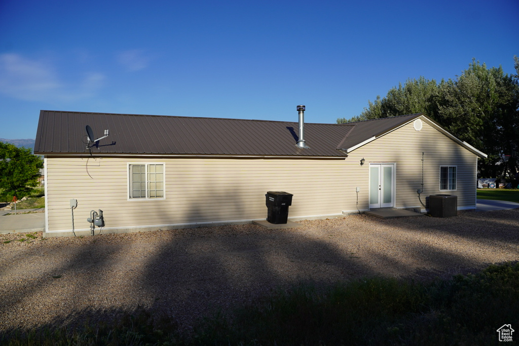 Back of property with central AC unit and metal roof
